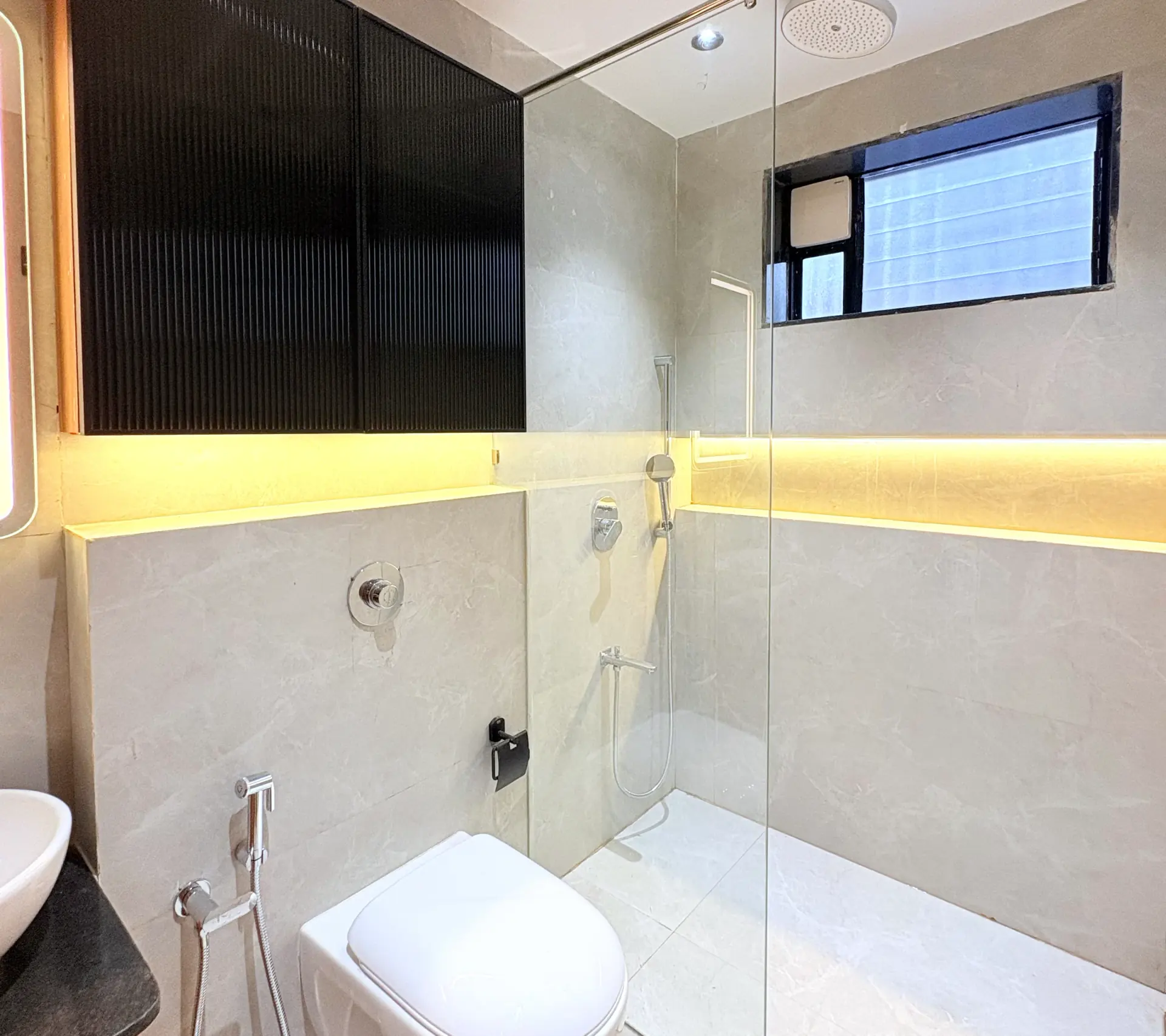 Walk-in shower behind clear glass in a stone-lined bathroom