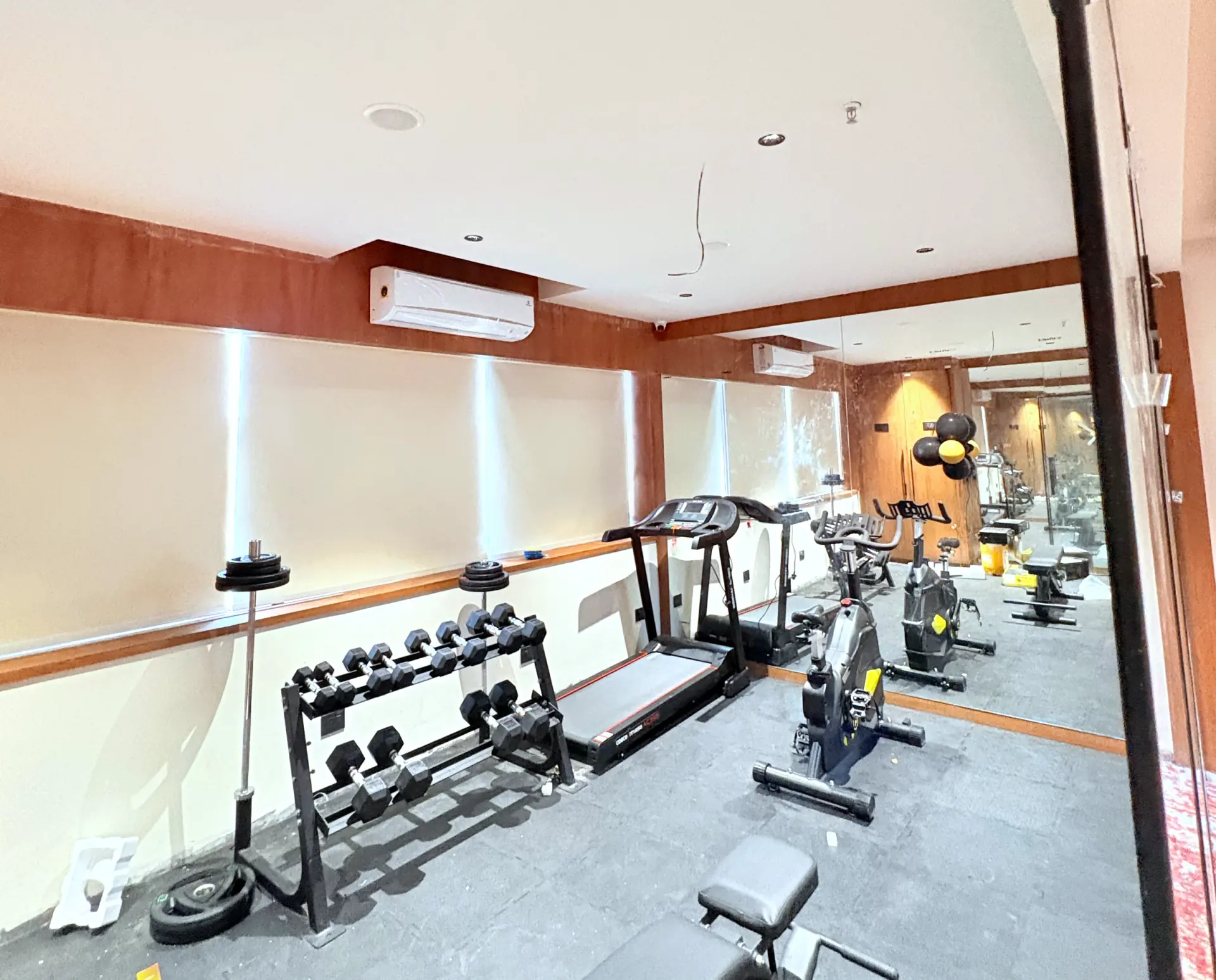 The fitness centre, cardio machines and a free-weight rack against a mirrored wall