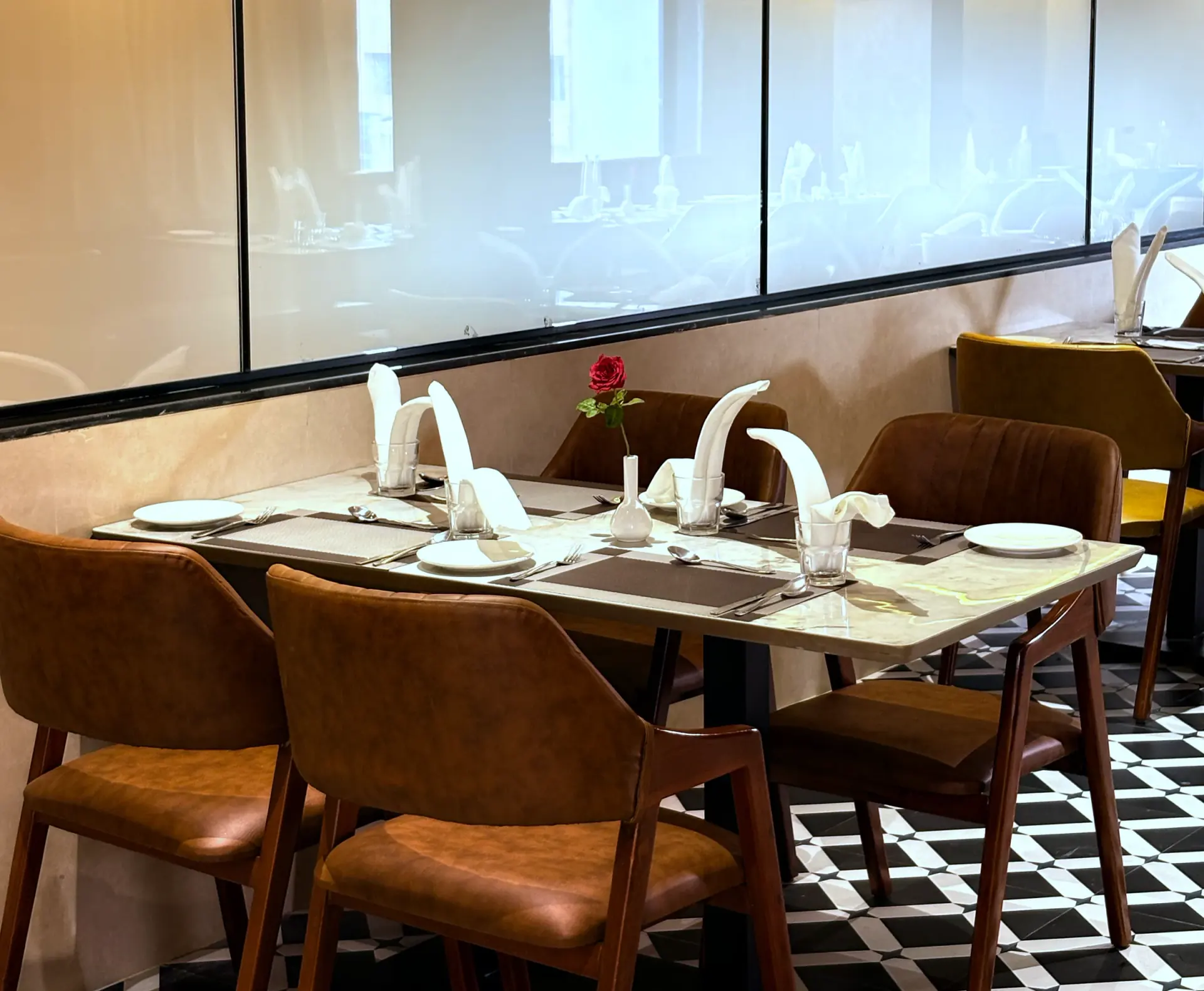 Restaurant tables laid with folded napkins and leather chairs