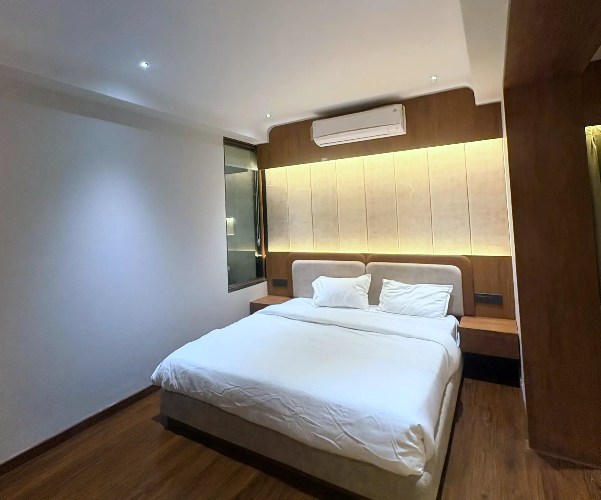 Executive Room with a double bed against a lit timber headboard wall