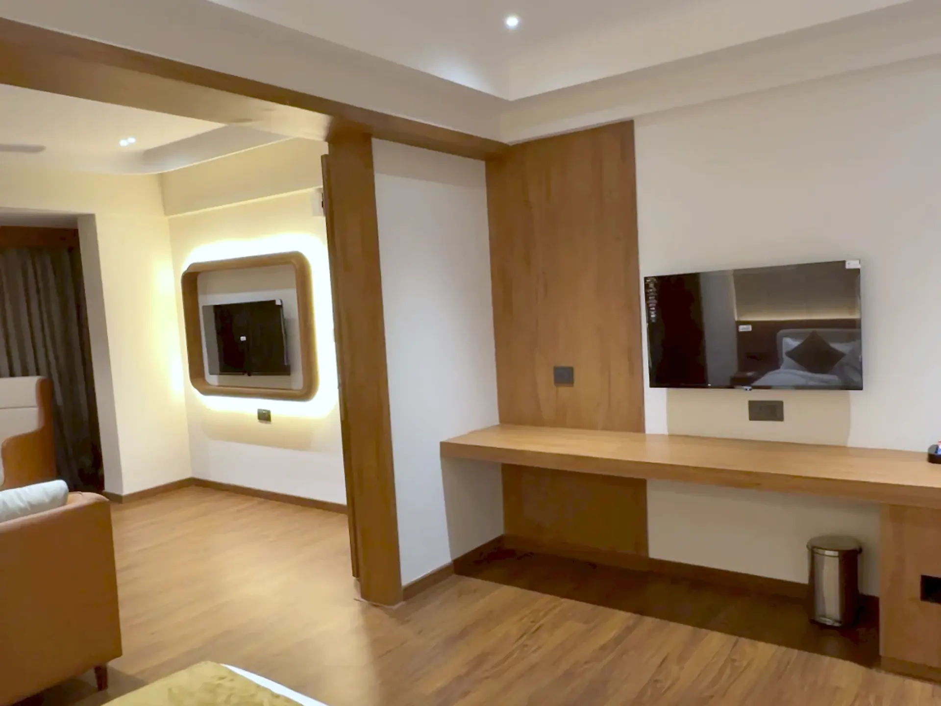 Suite bedroom with a work desk and television, the living room visible through the connecting doorway