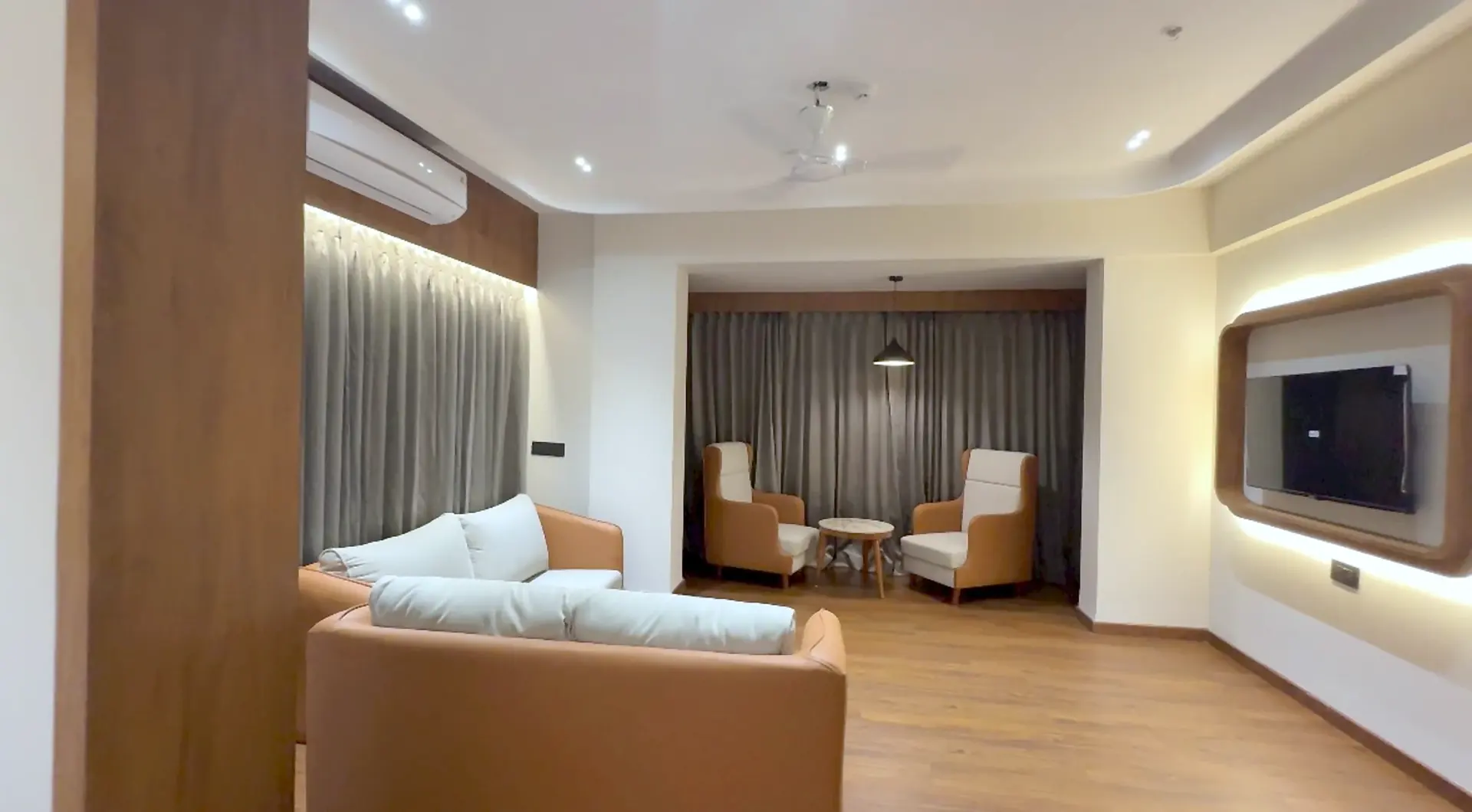 Majestic Suite living room with leather sofas, a lit television wall and two armchairs by the curtains