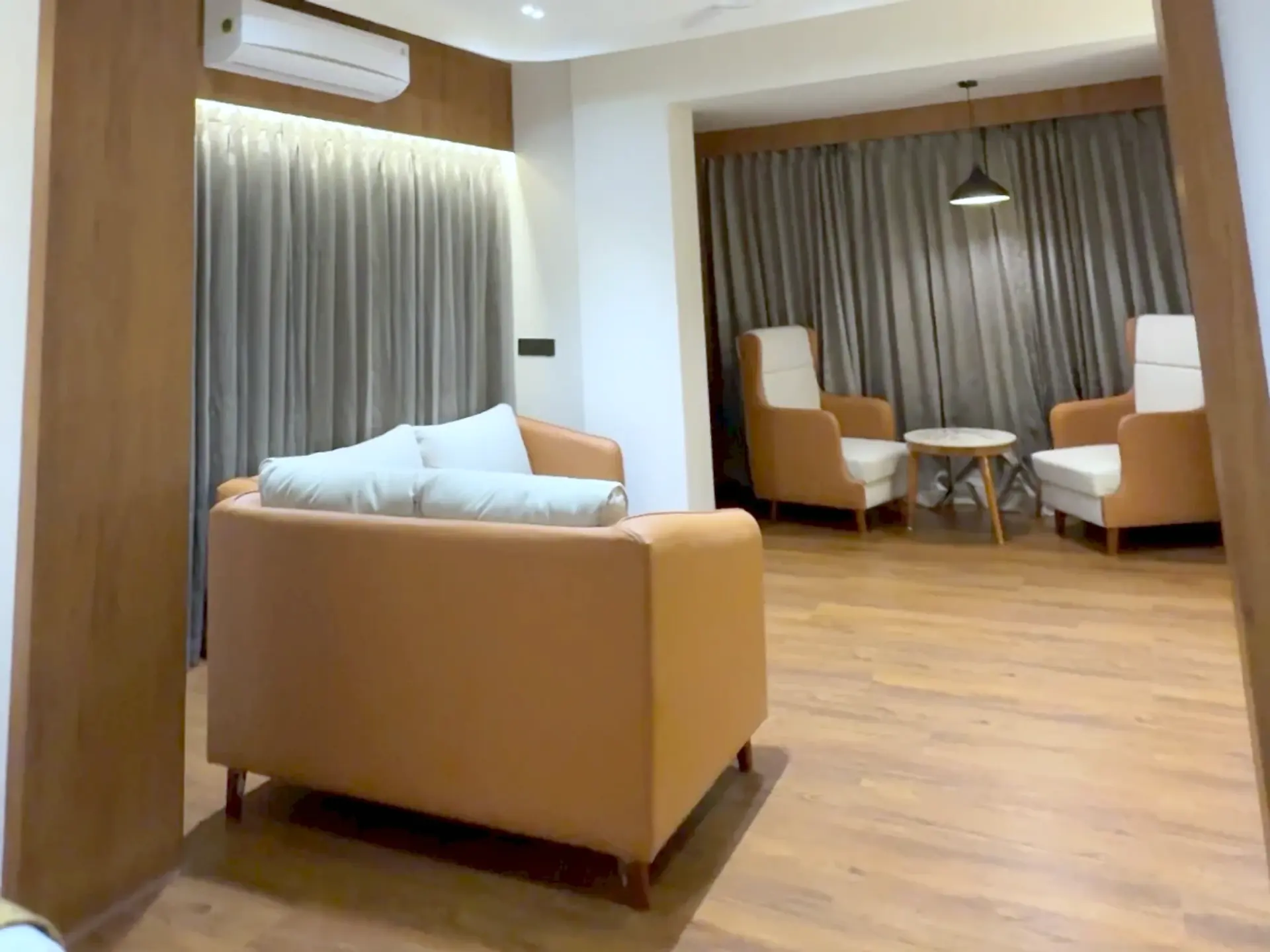 Suite sitting area seen through a timber archway: a leather sofa, two armchairs and a round side table